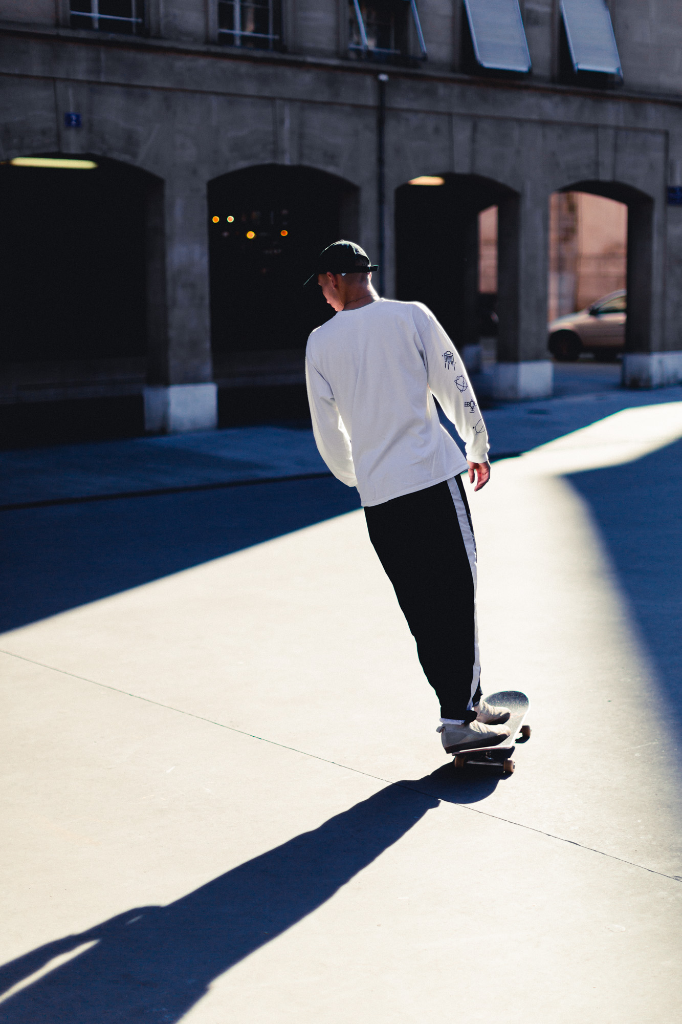 photo d'un skateur sur une planche de skate dos au soleil, projetant son ombre au sol