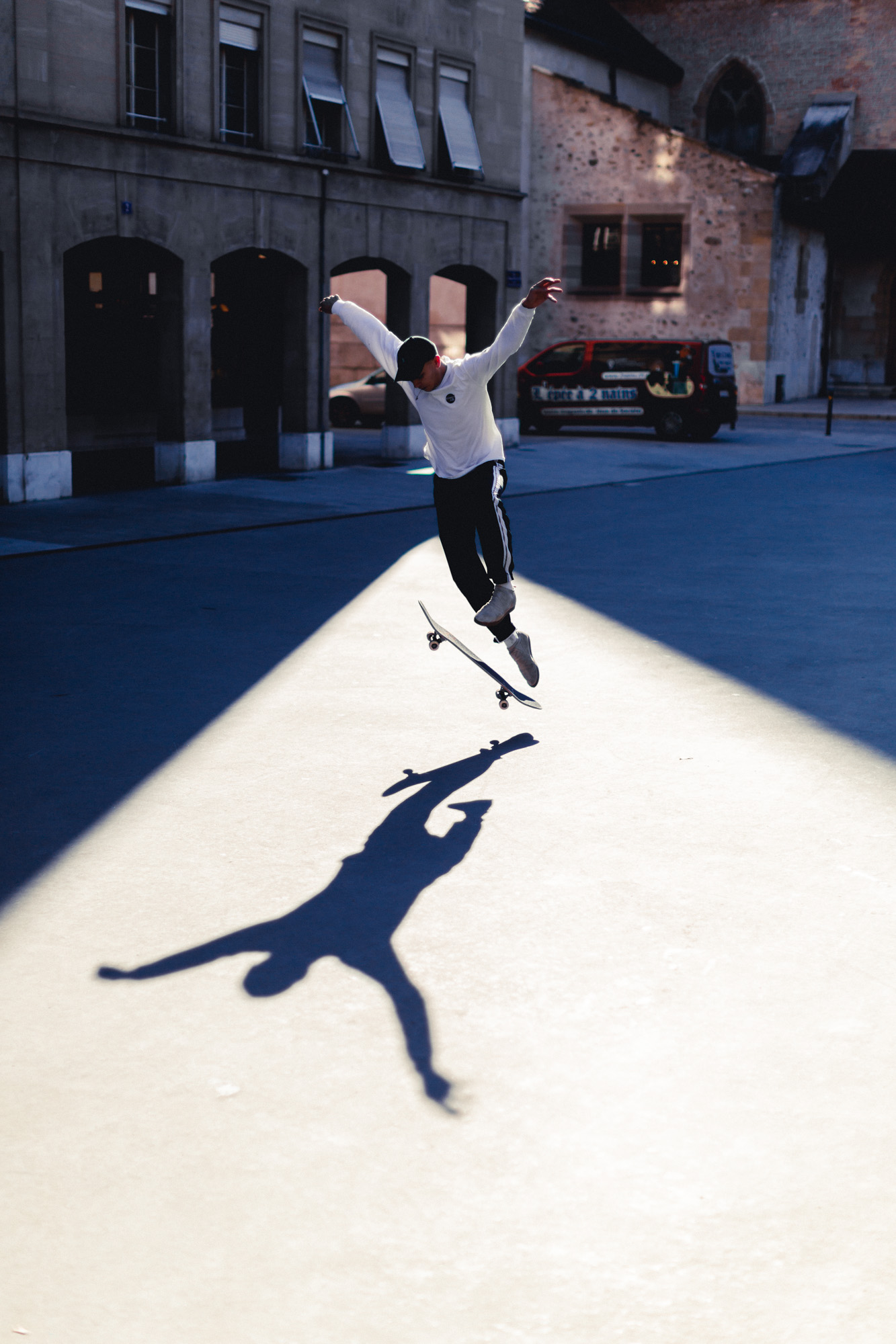 photo d'un skateur entrain de faire une figure de skate dos au soleil, bras écartés projetant son ombre au sol