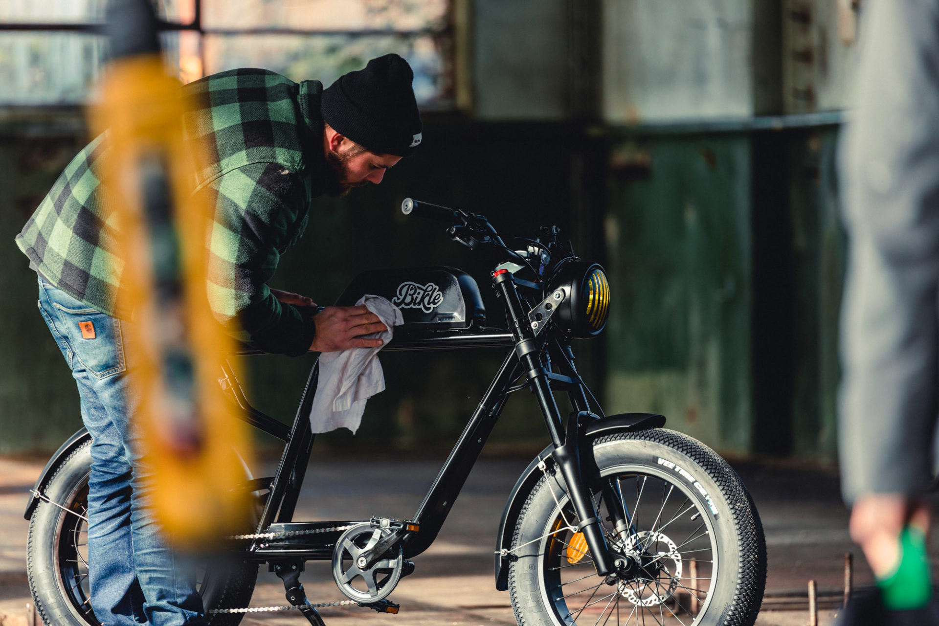 photo d'une personne nettoyant un vélo électrique noir ressemblant à une vieille moto