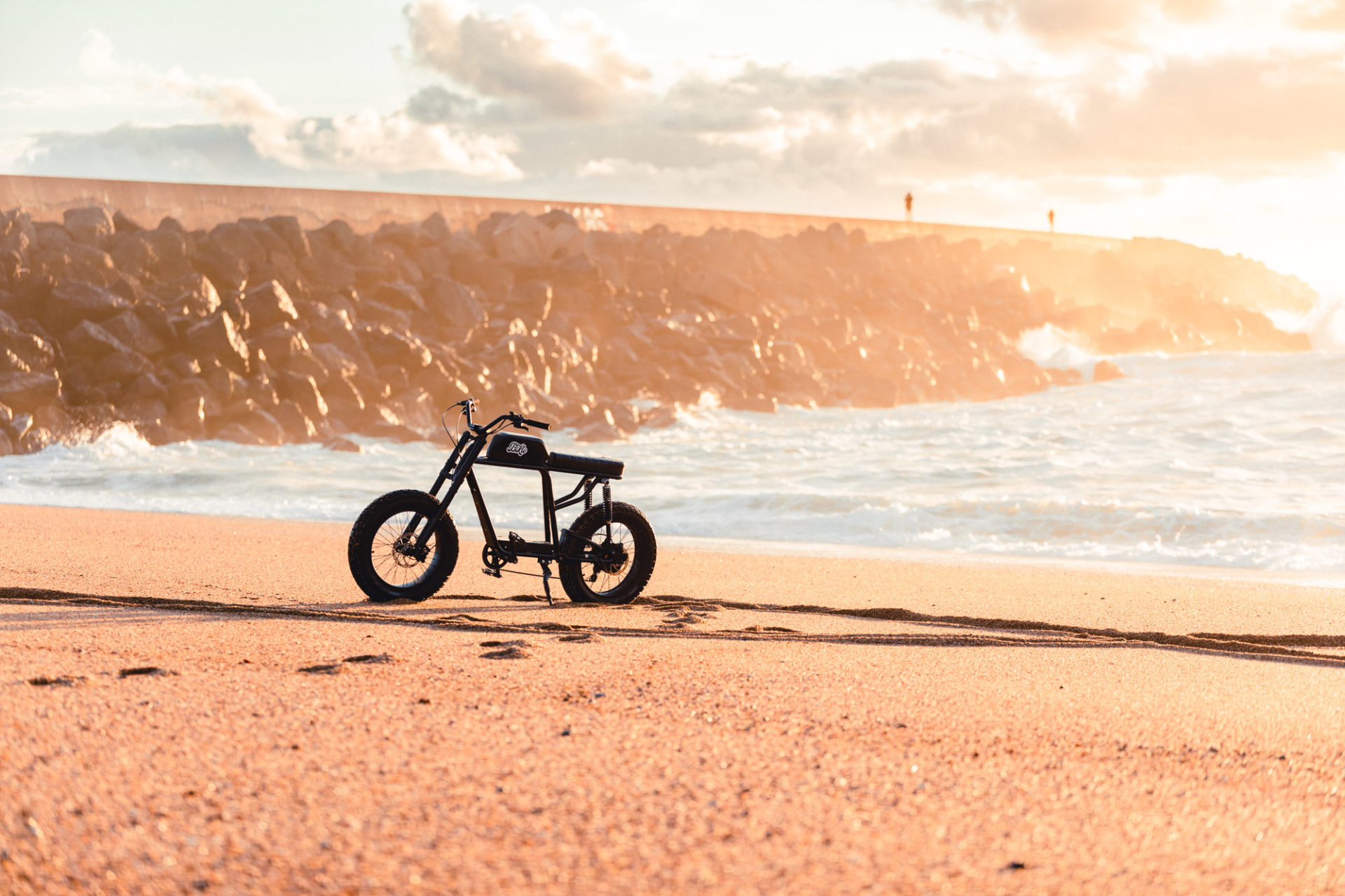 photo d'un vélo électrique ressemblant à une vieille moto sur du sable de plage, au bord de la mer